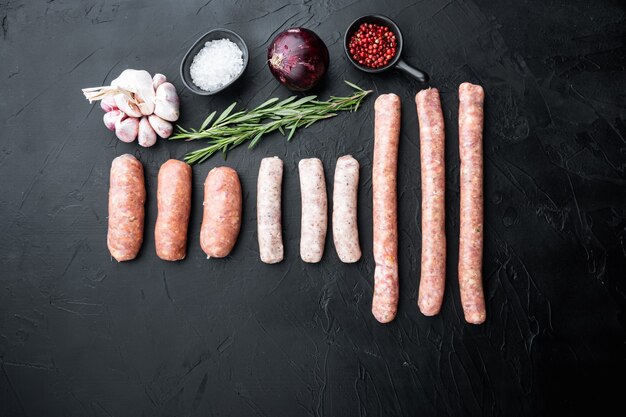 Assorted raw homemade sausages, flat lay, on black background