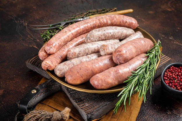 Assorted raw homemade sausages with Beef pork lamb and chicken meat on a plate Dark background Top view