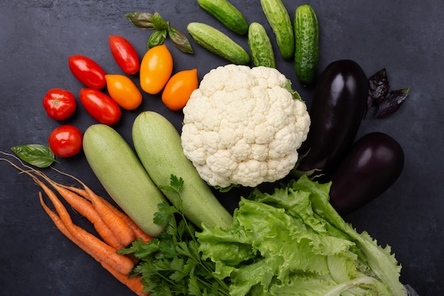 Assorted raw organic vegetables on dark stone