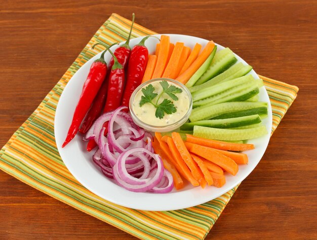 Assorted raw vegetables sticks in plate on wooden table close up