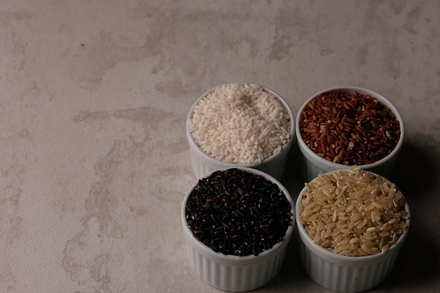 Assorted of rices, black rice, brown rice, purple rice, and\
white. staple food. fiber and carb.