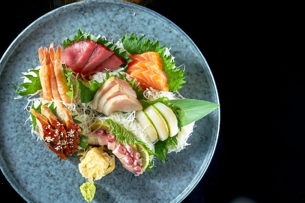 Sashimi assortito di salmone, gamberi, tonno, polpo, capesante e anguilla. cucina giapponese classica. consegna del cibo. isolato su nero