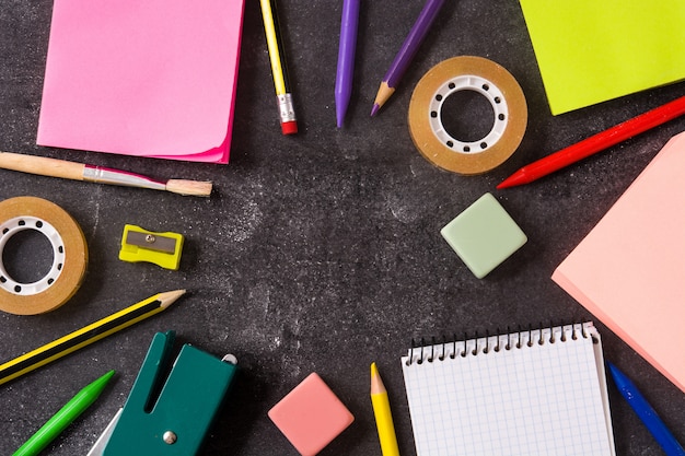 Assorted of school supplies on black slate Back to school concept