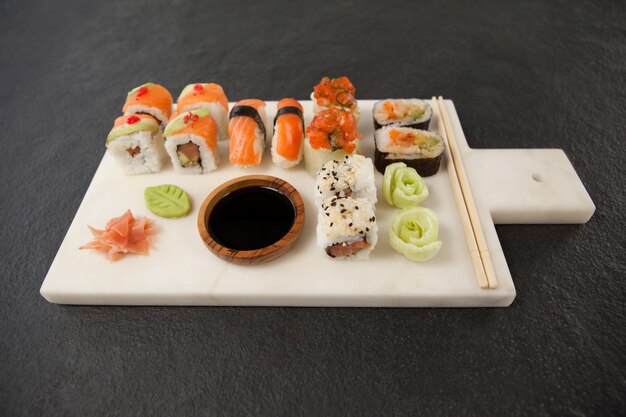 Assorted sushi set served with soy sauce and chopsticks on white board