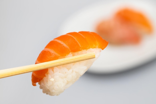 Foto sushi assortiti su un piccolo piatto bianco e uno con il bastone