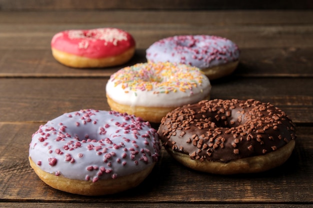 Assorted sweet donuts with icing and sprinkles on a brown wooden table