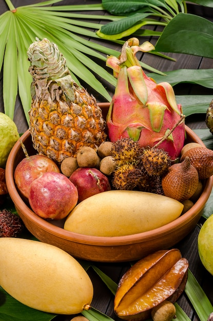 Foto frutta tropicale tailandese assortita su un fondo rustico di legno scuro.