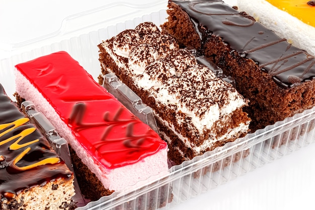 Assorted Tiramisu cakes in transparent plastic box on white