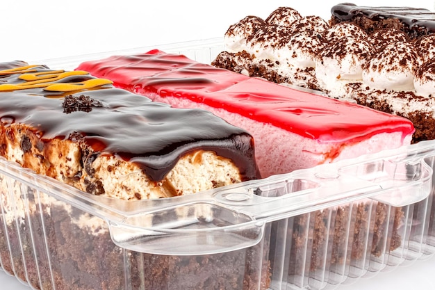 Assorted Tiramisu cakes in transparent plastic box on white