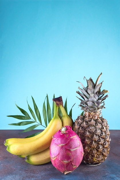 Assorted tropical fruits pineapple, mango, dragon fruit, on stone background. Group of exotic tropical fruits. Vegetarian healthy concept