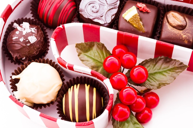 Assorted truffles in candy cane box on a white background.