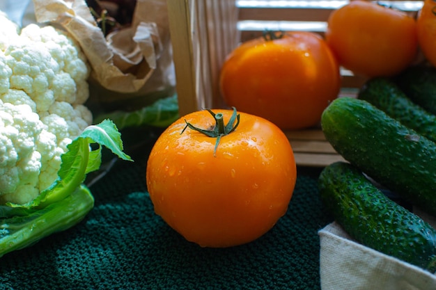 Assorted vegetables from tomatoes cucumbers and cauliflower on agreen tablecloth