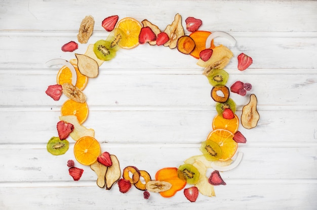 Assortied dried chips and ripe fruits on grey background