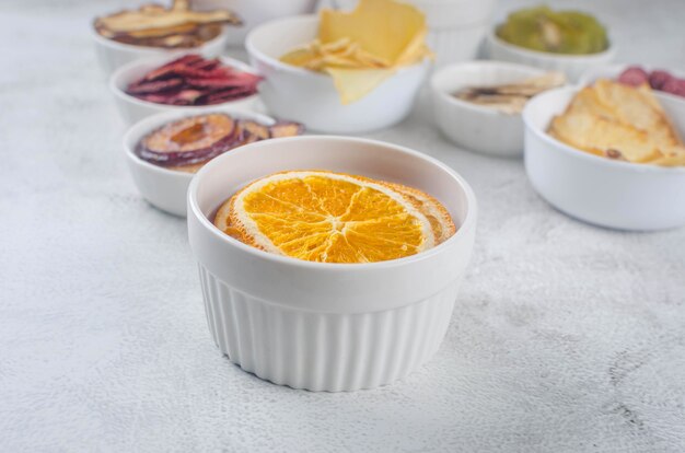 Assortied dried chips and ripe fruits in plates on grey background. Fruit chips. Healthy eating concept, snack, no sugar. Top view, copy space.