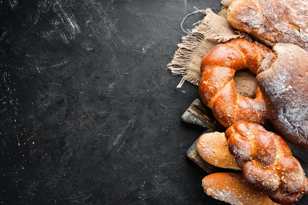 Assortiment van brood en bakken op een zwarte stenen achtergrond Bovenaanzicht Vrije ruimte voor uw tekst