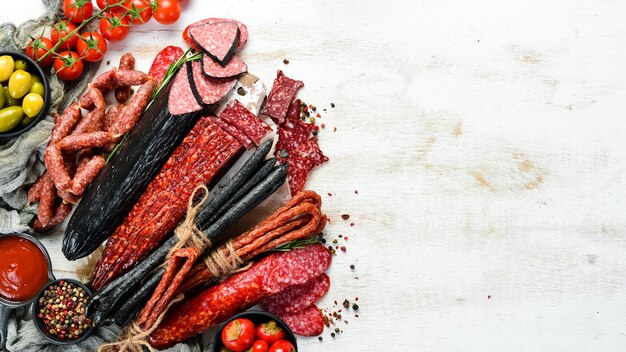 Assortiment van gedroogde salami en rookworst op witte houten achtergrond Bovenaanzicht Vrije ruimte voor uw tekst