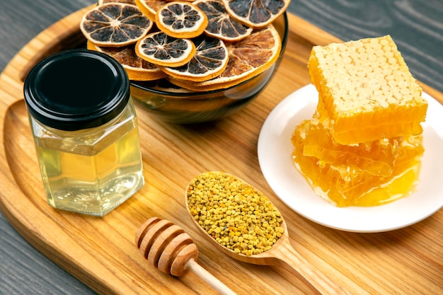 Assortiment van noten en diverse gedroogde citrusvruchten en verse bloemen honingraat honing en stuifmeel op keuken houten plank nuttige vitamine voedsel voor het menselijk lichaam