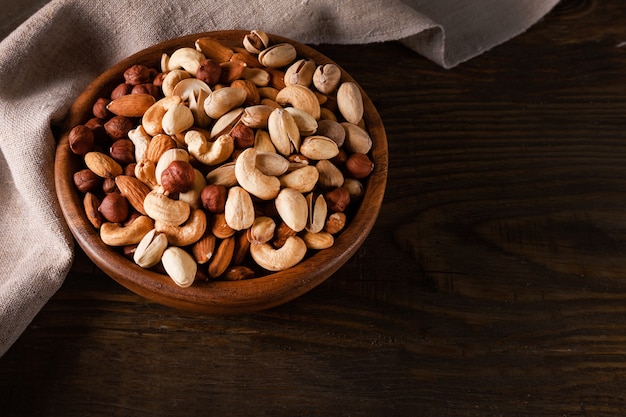 Assortiment van noten in houten kom op donkere houten tafel. Cashewnoten, hazelnoten, amandelen en pistachenoten.