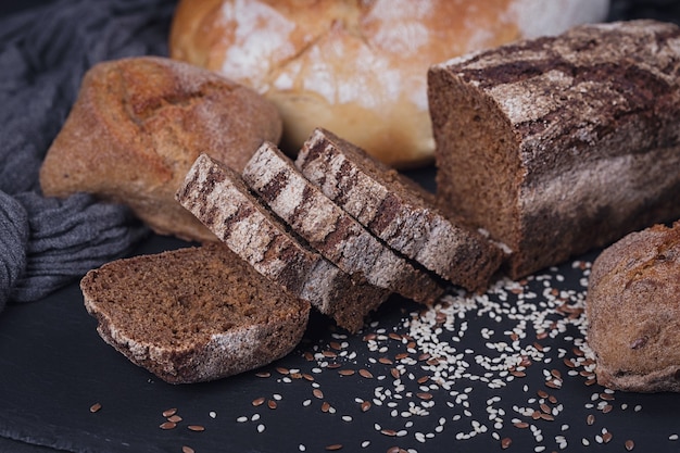 Assortment of baked bread on dark background. Bakery and grocery food store concept.