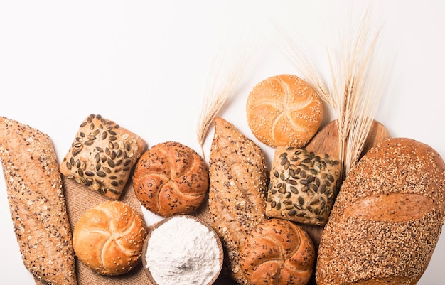 Assortment of baked bread with seeds on a white table background. Bakery. Food security concept.