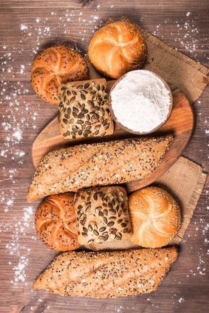 Assortment of baked bread with seeds on a wooden table background. Bakery. Food security concept.