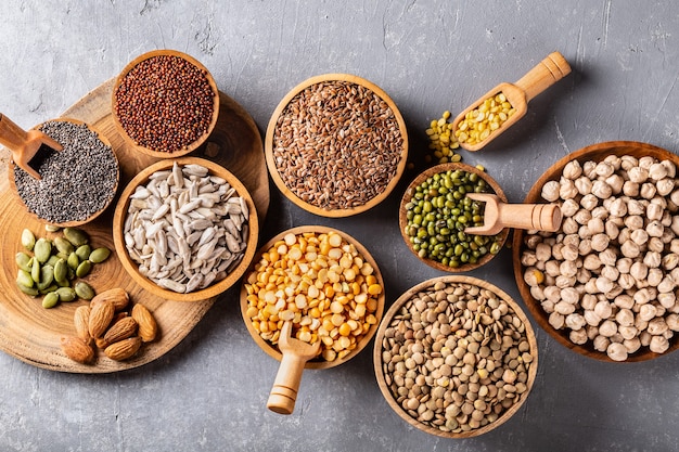 Assortment of beans, seeds, legumes on grey concrete background.