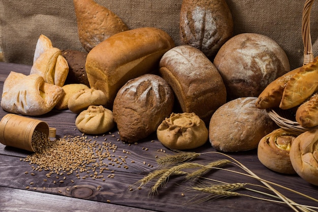 Assortment of bread ears and grains of wheat on wooden table Rustic style