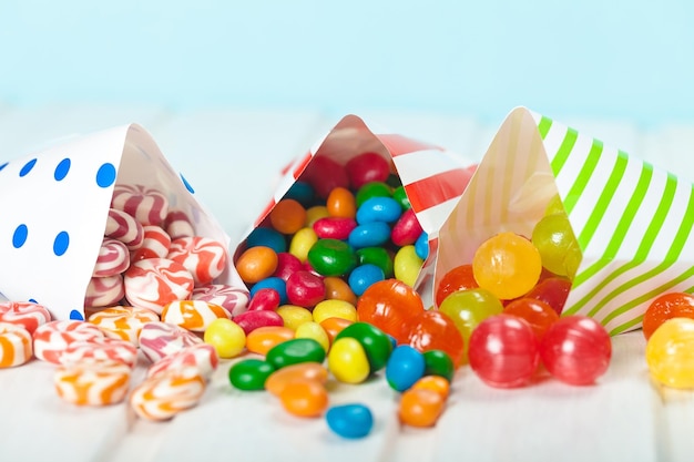 Assortment of candies in three striped decorated bags scattered over a white wooden table