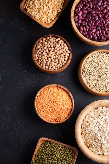 Assortment of cereals, legumes, cereals, grains, lentils, chickpeas, peas, beans, oatmeal in wooden bowls