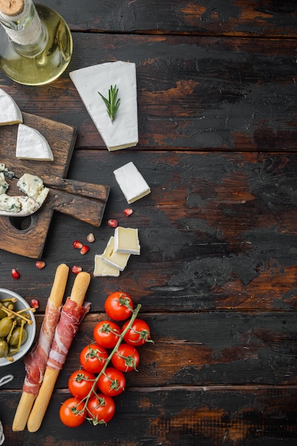 Assortment of cheese and meat appetizers set, on dark wooden, flat lay  