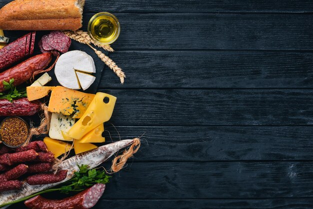 Assortment of cheeses and traditional sausages on a wooden background Brie cheese blue cheese gorgonzola fuete salami Free space for text Top view