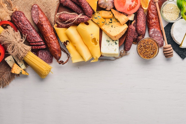 Assortment of cheeses and traditional sausages on a wooden background Brie cheese blue cheese gorgonzola fuete salami Free space for text Top view