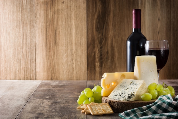 Assortment of cheeses and wine on wooden table. Copy space