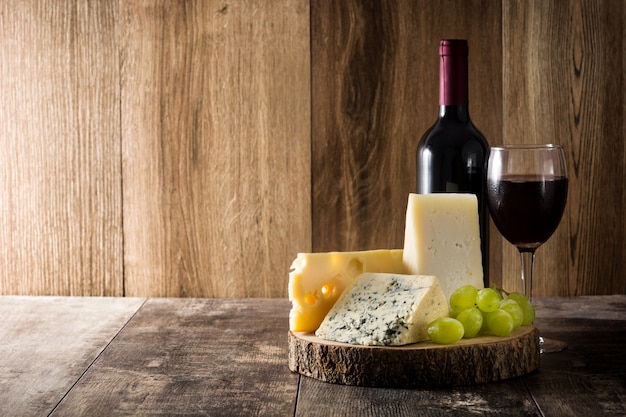 Assortment of cheeses and wine on wooden table. Copyspace