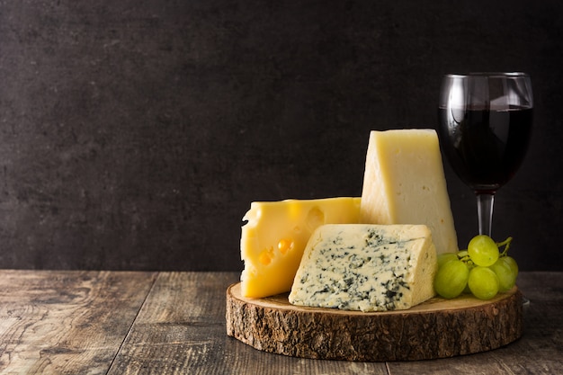 Assortment of cheeses and wine on wooden table.