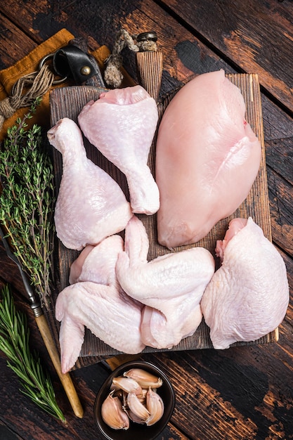 Assortment of chicken portions for Bbq grilling Raw parts drumstick breast fillet wings thigh Wooden background Top view