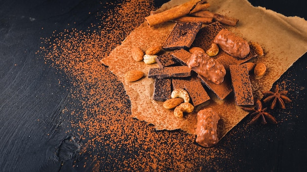 Assortment of chocolates with nuts Black and milk chocolate Wooden on the black surface Top view