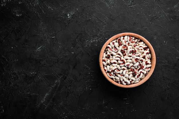 Assortment of colored raw beans On a black stone table Top view Free copy space