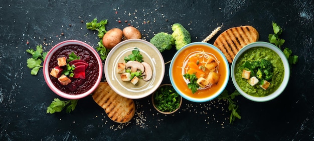 色付きの野菜クリームスープの品揃えダイエット食品黒い石の背景に上面図無料コピースペース