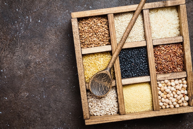 Assortment of different cereals and seeds in a box on dark brown