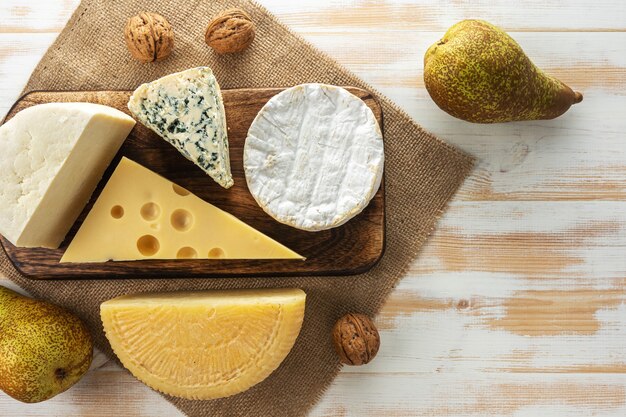 Assortment of different cheese types on white wooden table.