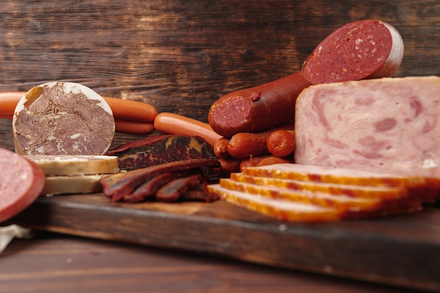 Assortment of different sausages laid out on brown wooden background