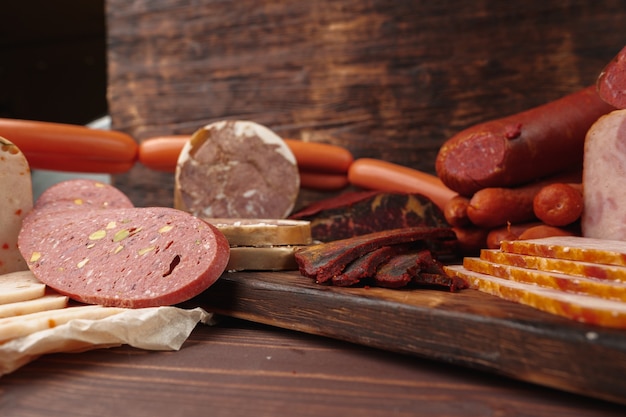 Assortment of different sausages and meat laid out on brown wooden background