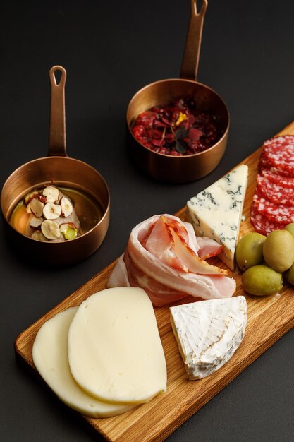 Assortment of different types of cheese and sausages served with sauces Cheese board