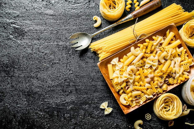 Assortment of different types of dry pasta on a plate with ladle