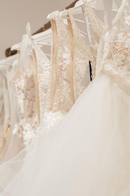 Assortment of dresses hanging on a hanger on the background studio Fashion wedding trends Interior of wedding shop