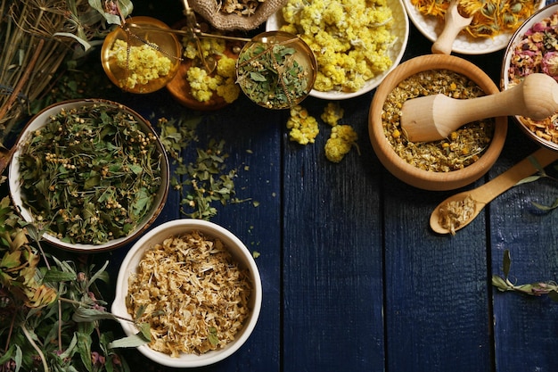 Photo assortment of dry medicinal herbs in bowls on wooden background top view