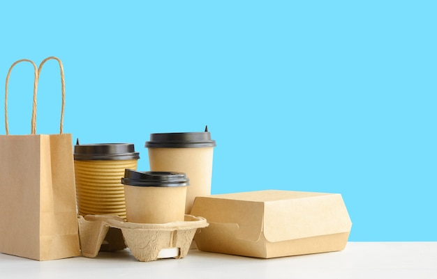 Assortment of food delivery containers on the table on blue wall background copy space