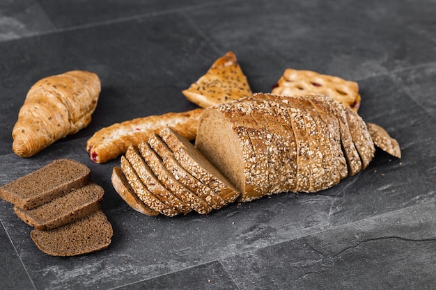 Assortment of fresh baked bread on dark background White and rye bread buns with copy place