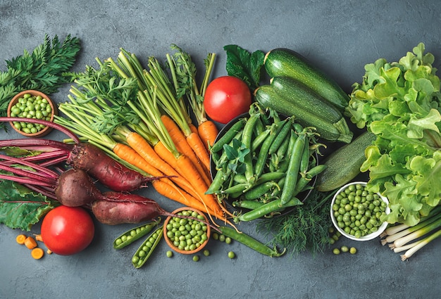 An assortment of fresh vegetables on a gray-blue background. Top view, copy space. Tinted image.